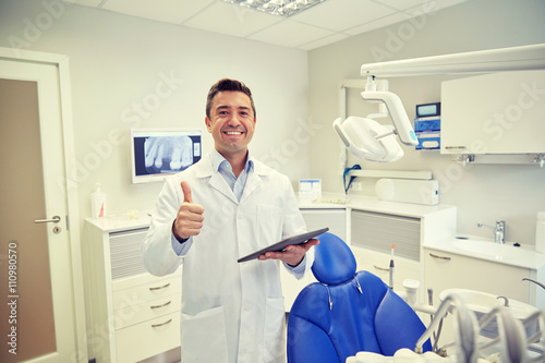 happy dentist showing thumbs up with tablet pc