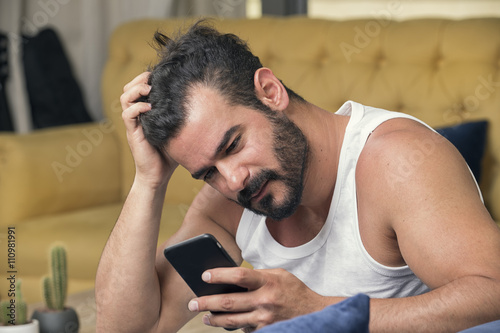 Handsome guy using smartphone, Handsome man sitting on couch at