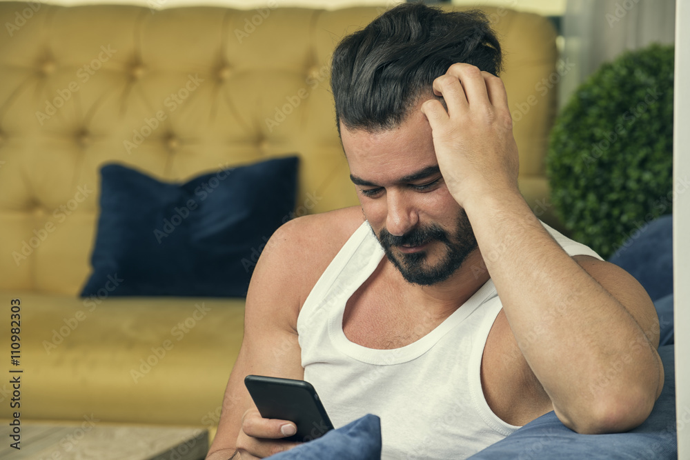 Handsome guy using smartphone, Handsome man sitting on couch at