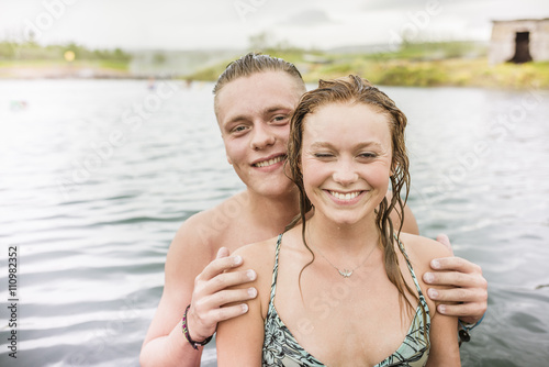 Portrait of smiling young couple standing in Secret Lagoon hot spring (Gamla Laugin), Fludir, Iceland photo