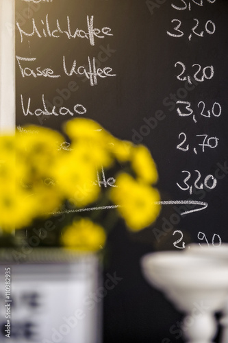 Yellow flowers in front of cafes chalkboard menu, focus on background photo