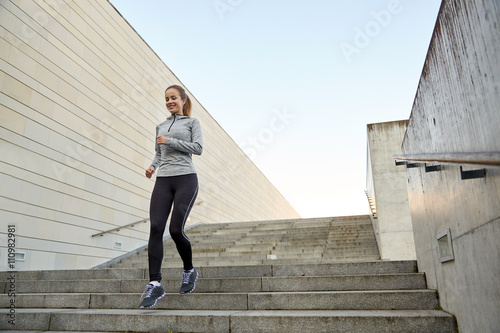 happy sporty woman running downstairs in city