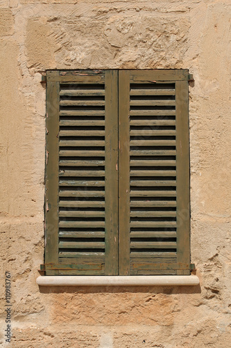 window with vintage shutter in stone wall