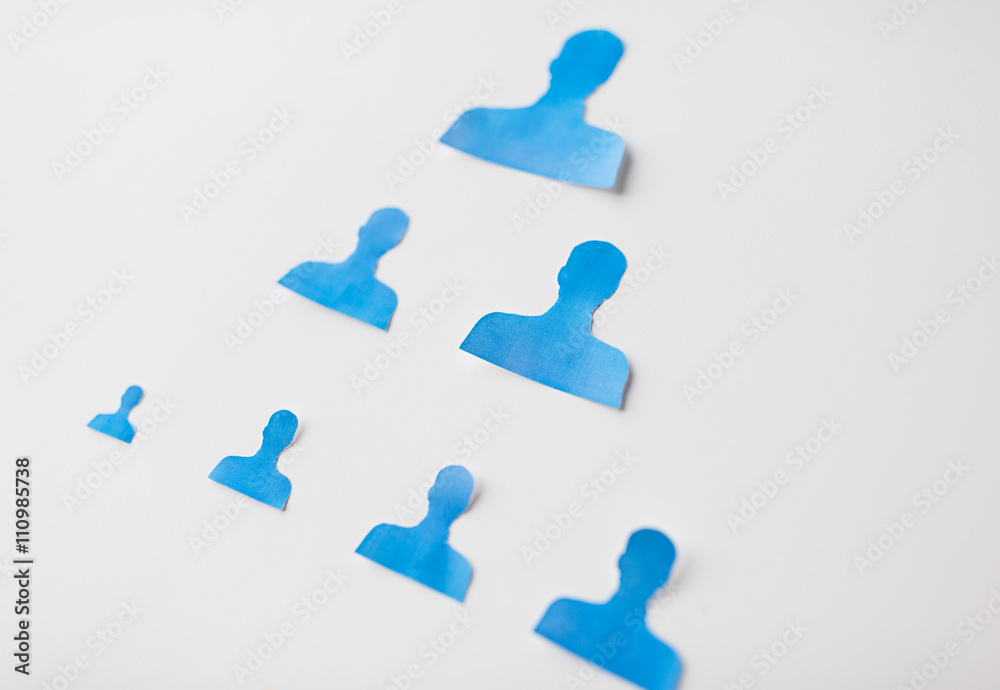 close up of paper human shapes on white board close up of paper human shapes on white board