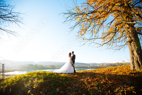 Happy handsome groom and beautifyl bride hugging on balcony at sunset closeup