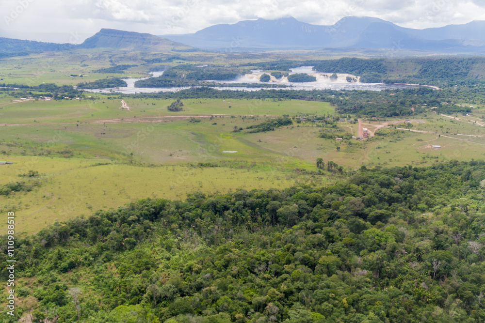 Aerial view of Canaima Lagoon waterfalls at river Carrao in Venezuela. Tepuis (table mountains) in the background