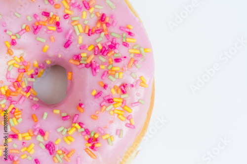 A large doughnut with hole and pink icing with sprinkles on an isolated white background.