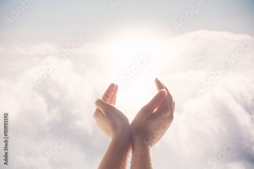Hands raised up on a background of blue sky