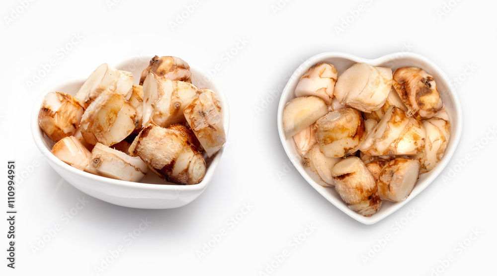 Fresh galangal  in a heart shaped bowl, isolated on white