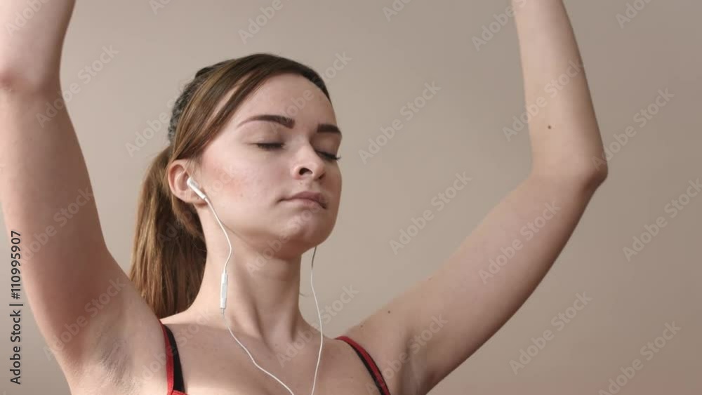 Meditating girl in earphones raising hands in lotus position Meditating girl in earphones raising hands in lotus position