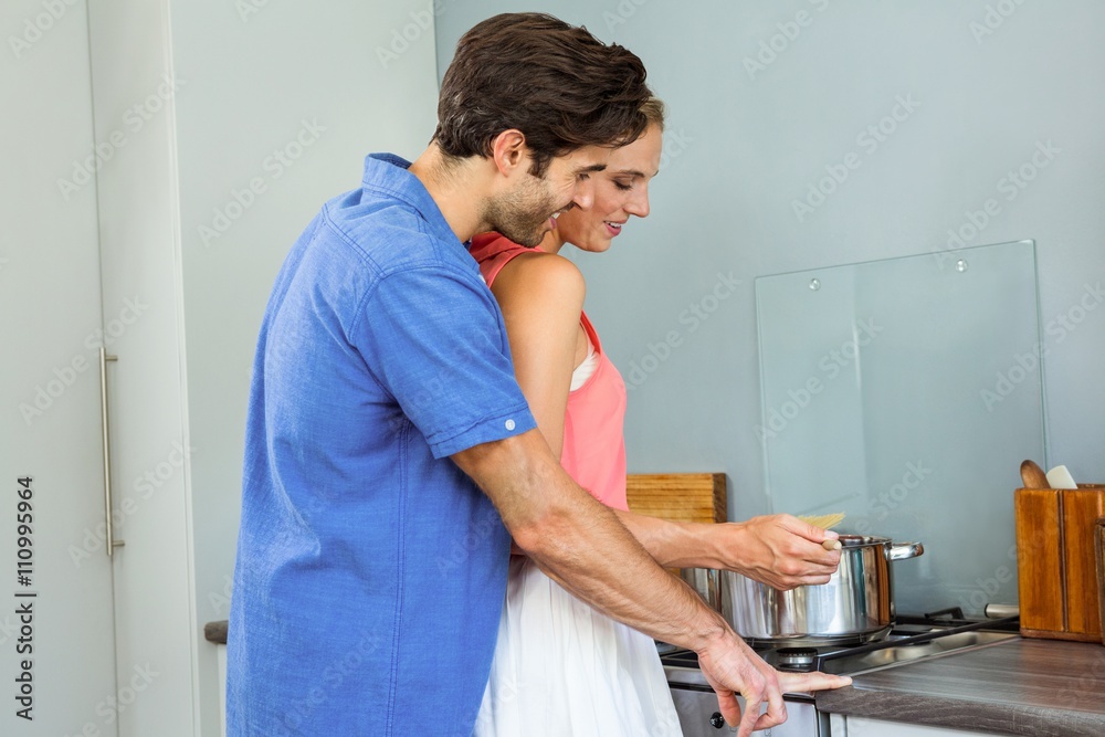 Young couple preparing food together in kitchen Young couple preparing food together in kitchen
