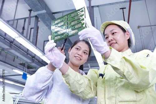 Supervisor overseeing work at quality check station at factory producing flexible electronic circuit boards. Plant is located in the south of China, in Zhuhai, Guangdong province photo