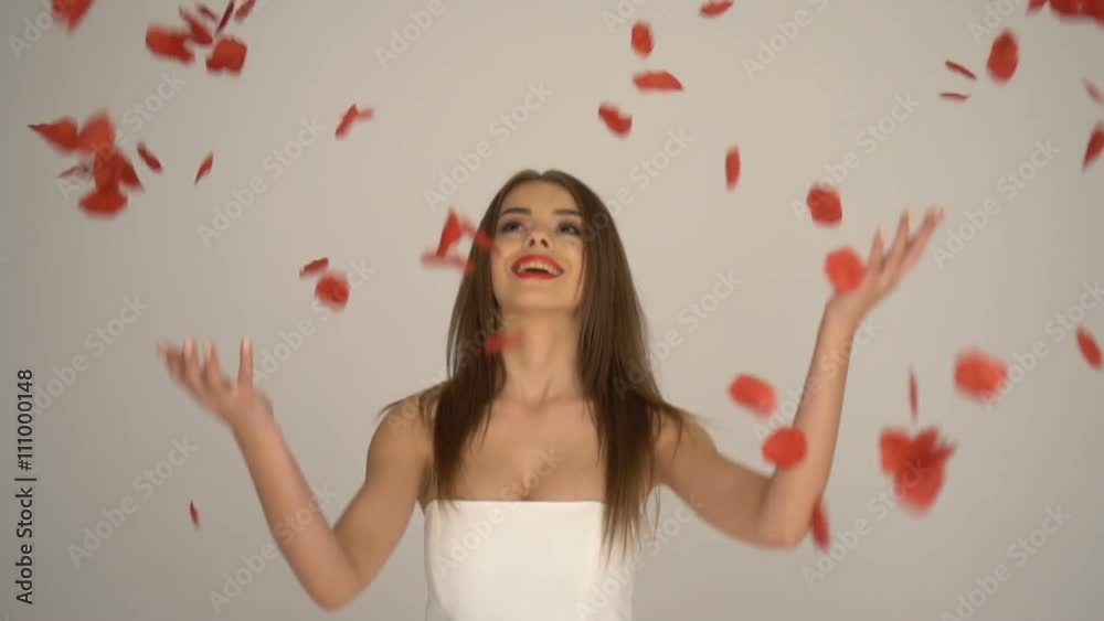 beauty brunette woman with rose petals falling down wearing white dress beauty brunette woman with rose petals falling down wearing white dress