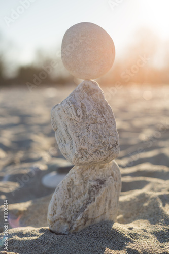 Sculpture made with stack stones in equilibrium close to the shore on a sandy beach.