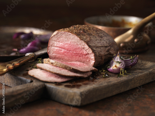 Christmas dinner. Chateaubriand steak cooked with a thick cut from the tenderloin filet, rare medium served with roasted onions, pepper and herbs photo