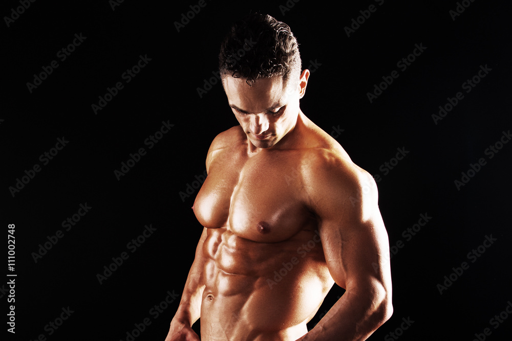 Strong Athletic Man showing muscular body on a black background.Muscular man on black background Strong Athletic Man showing muscular body on a black background.Muscular man on black background