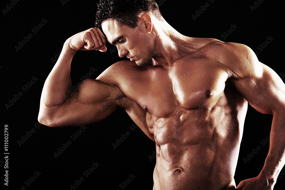 Strong Athletic Man showing muscular body on a black background.Muscular man on black background Strong Athletic Man showing muscular body on a black background.Muscular man on black background