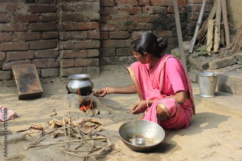 Cooking. A woman is cooking rice in a remote village. Food is our necessity. The woman is cooking rice with the help of natural equipment.