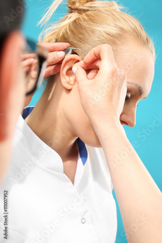 Zakładanie aparatu słuchowego.Lekarz zakłada kobiecie aparat słuchowy na ucho 