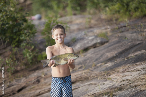 Teenage boy holding up smallmouth bass fish, Lake Superior, Au Train Bay, Michigan, USA photo