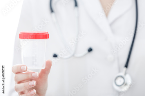Women doctor holds test container in her hand.