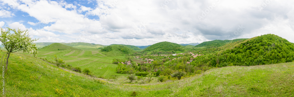 Old small traditional village in a beautiful valley in Transylvania region of Romania. A beautiful wide panoramic perspective from abive with a small traditional rural settlement