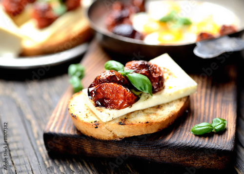 toast with cheese, tomato and basil on a wooden background