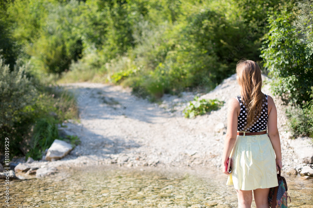 Young hipster woman hiker with bag enjoying on a stream in natur