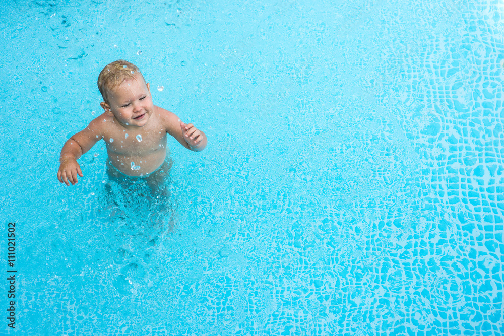 Cute happy little boy swimming in swimming pool