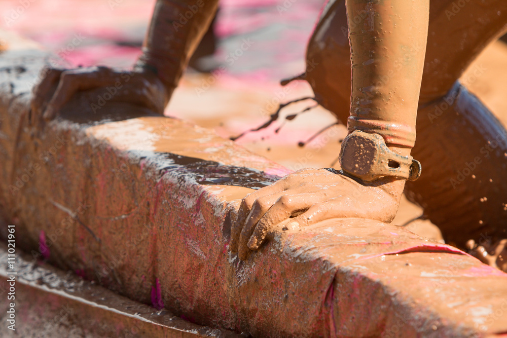 Closeup Female Muddy Hands Grabbing Barrier At Mud Run Event Closeup Female Muddy Hands Grabbing Barrier At Mud Run Event