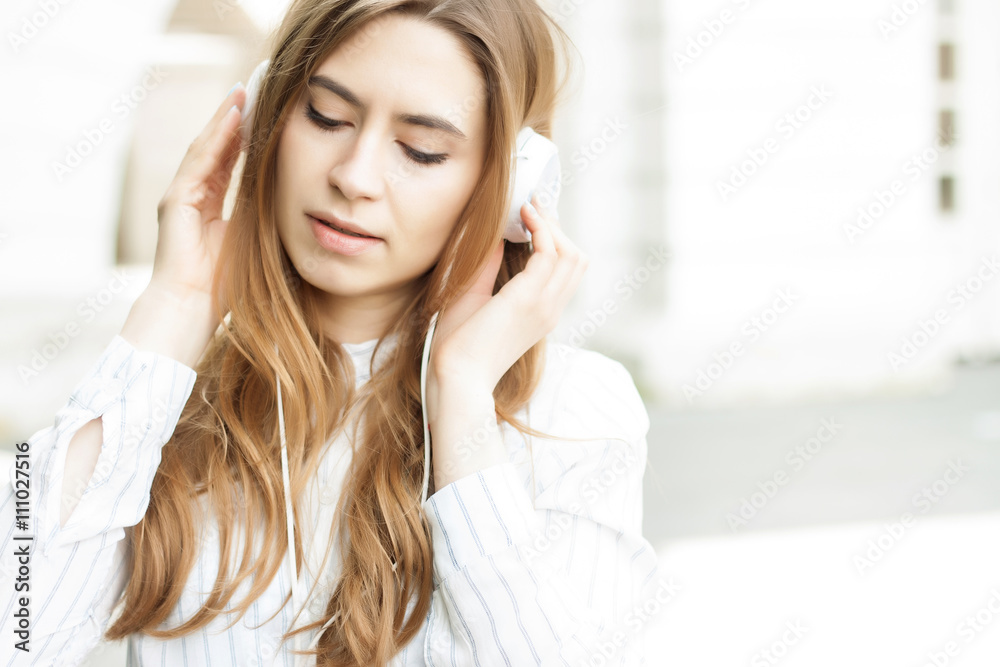 beautiful girl standing on the street with headphones and smilin beautiful girl standing on the street with headphones and smilin