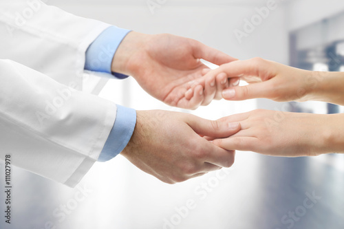 Male doctor holding patient's hands, on blurred background © Africa Studio