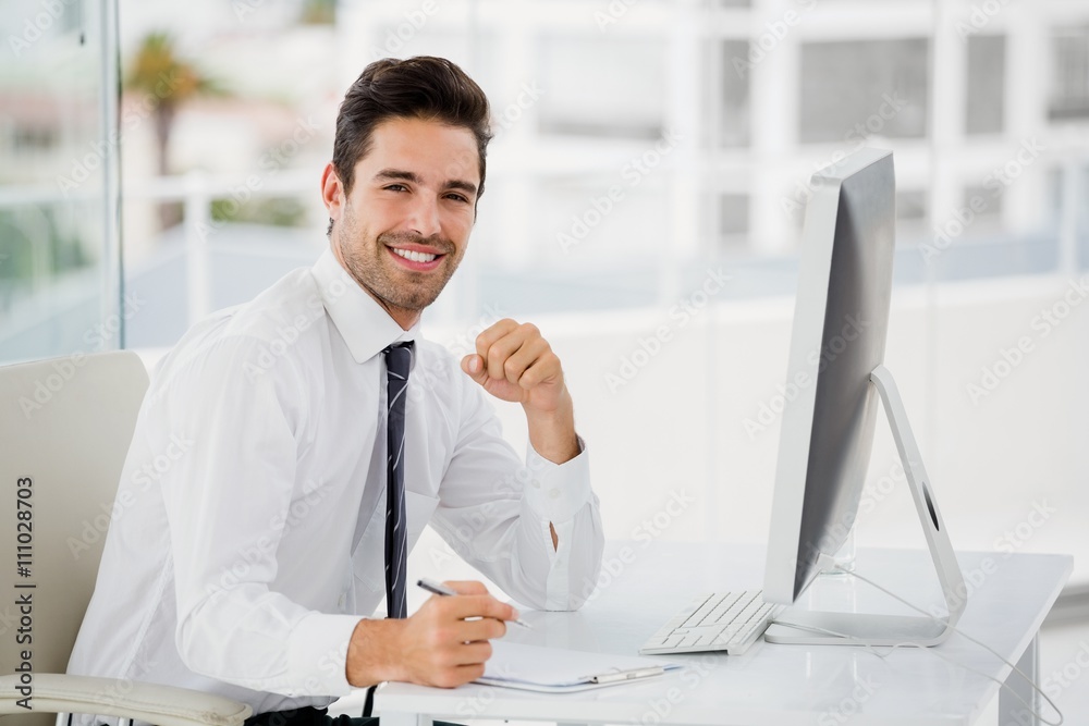Businessman using computer and taking notes