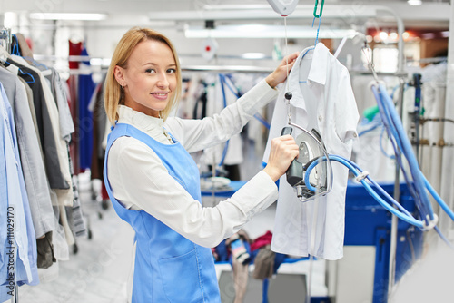 Girl worker Laundry ironed clothes and smiling at the dry cleaners