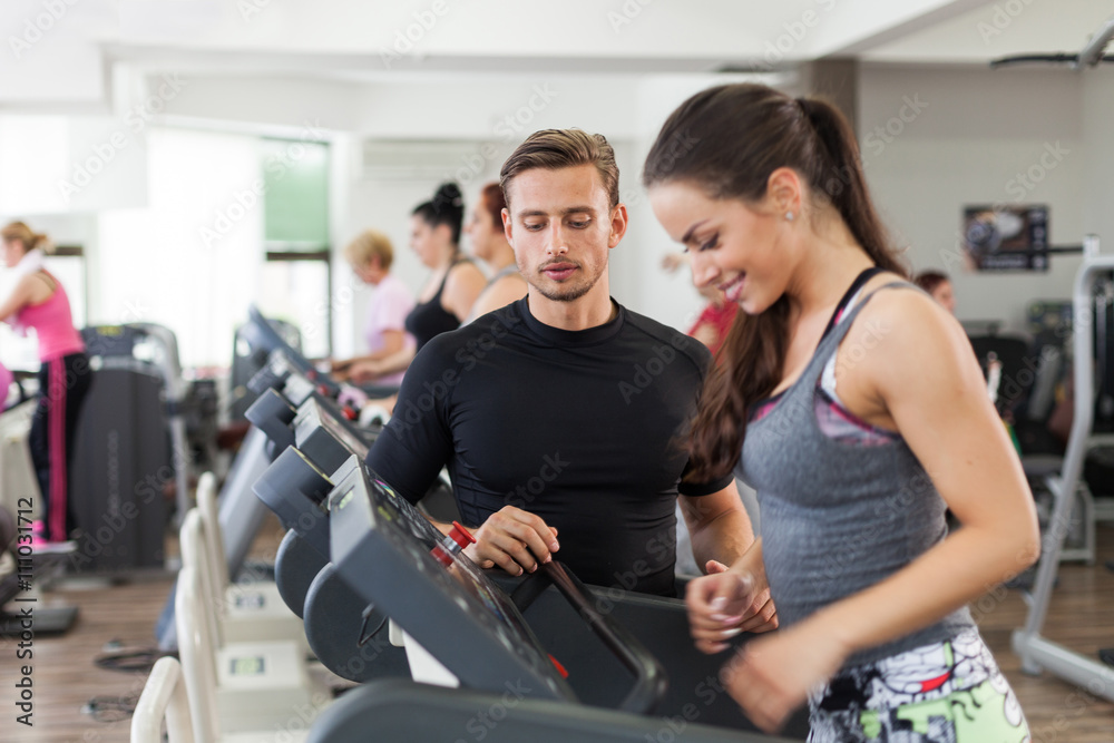 Happy coach assisting young woman in a gym