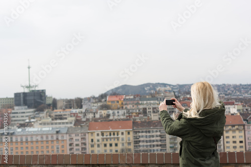 Beautiful young blonde tourist woman taking photographs.