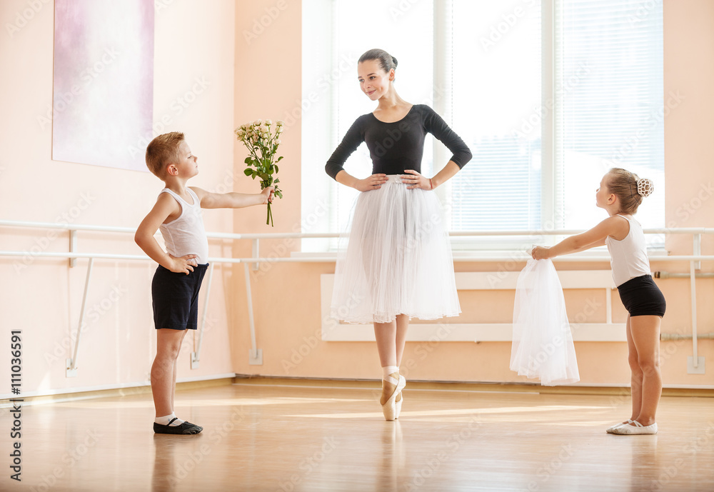 At ballet dancing class: young boy and girl giving flowers and veil to older student while she is dancing en pointe At ballet dancing class: young boy and girl giving flowers and veil to older student while she is dancing en pointe