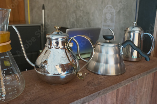 Shinny silver coffee pot as display on wooden table coffee bar in coffee shop or cafe or restaurant 