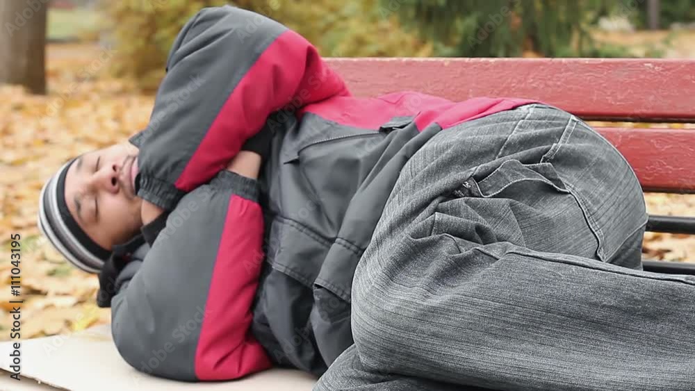 Vagabond in jacket and jeans sleeping on bench, trying to keep warm, poverty Vagabond in jacket and jeans sleeping on bench, trying to keep warm, poverty
