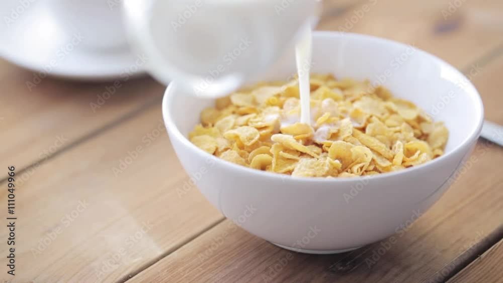 milk pouring to corn flakes on wooden table milk pouring to corn flakes on wooden table