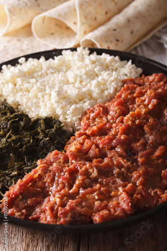 Ethiopian kitfo with herbs and cheese ayibe and injera close-up. Vertical
 photo