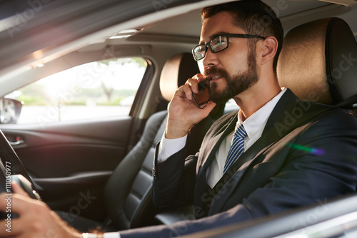 Business executive talking on phone when driving car © DragonImages