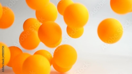 many orange balls falling and bouncing over the white surface slow motion