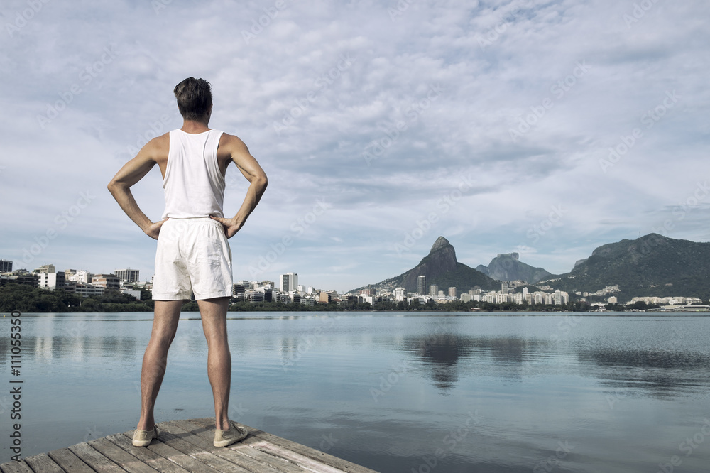 Athlete in white sport uniform standing with hands on hips in front of Rio de Janeiro Brazil skyline at Lagoa Rodrigo de Freitas lagoon Athlete in white sport uniform standing with hands on hips in front of Rio de Janeiro Brazil skyline at Lagoa Rodrigo de Freitas lagoon