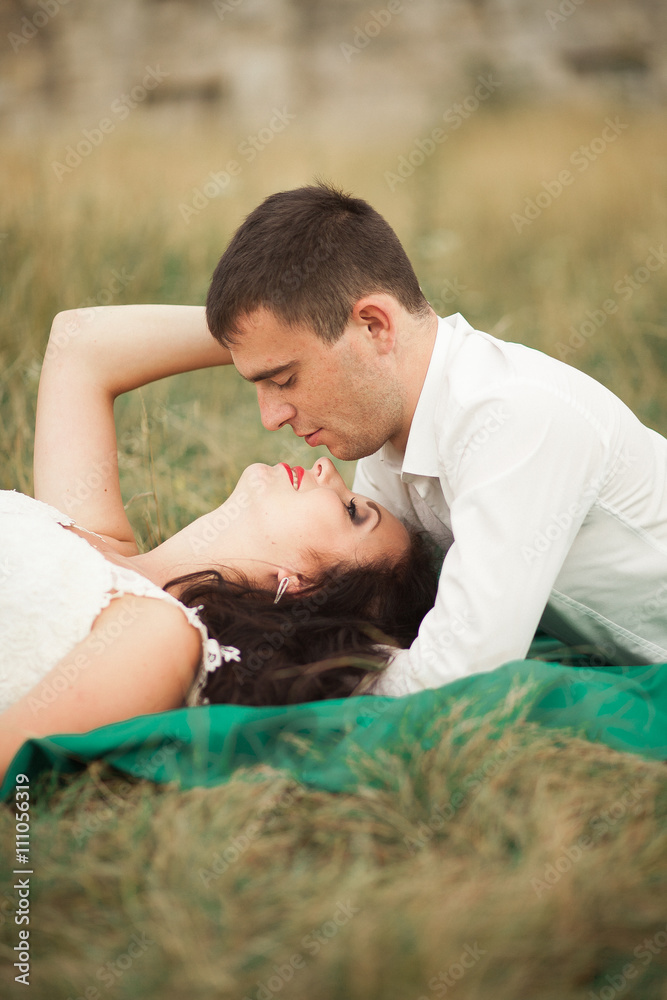 Happy wedding couple lying on green grass at the summer time Happy wedding couple lying on green grass at the summer time