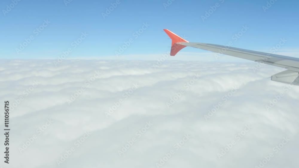 Flying in an airplane above the clouds. Fluffy white clouds view from above in sky. The wing of the plane cuts the atmosphere in the air Flying in an airplane above the clouds. Fluffy white clouds view from above in sky. The wing of the plane cuts the atmosphere in the air