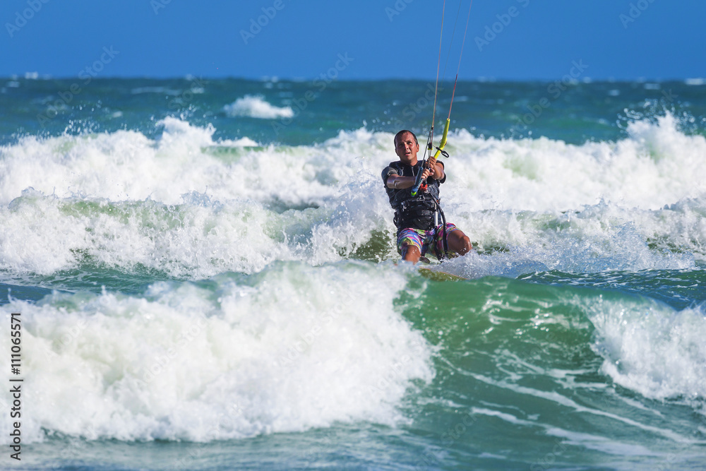 Athletic man riding on kite surf board at sea waves