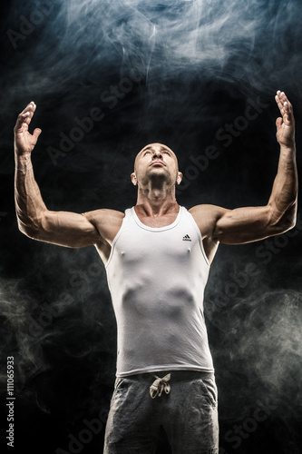 Muscular sportsman with arms raised looking up