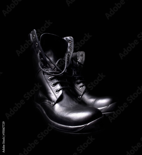 a pair of black leather military boots on black background photo