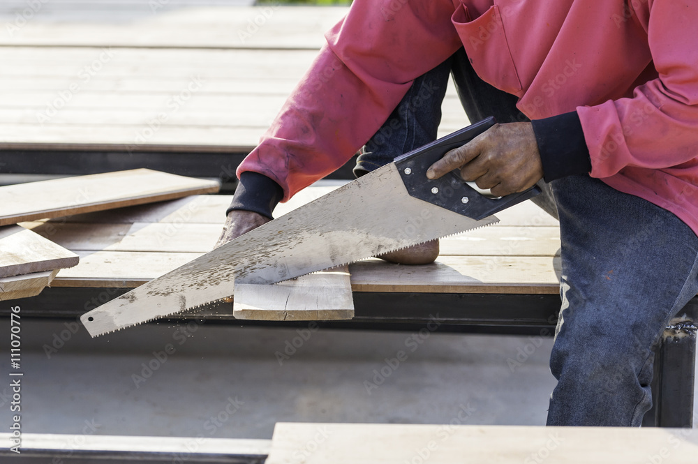 close up of Carpenter sawing a board with a hand wood saw